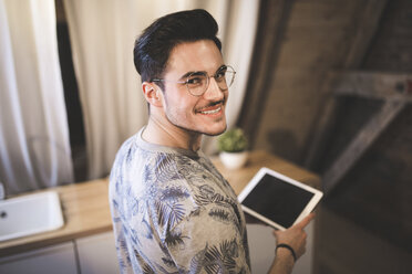 Porträt eines lächelnden jungen Mannes, der zu Hause ein Tablet benutzt - AWF00128
