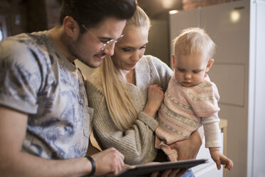 Young parents using tablet at home with their baby girl - AWF00130