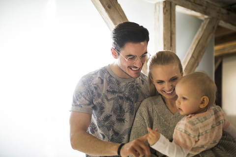 Glückliche junge Eltern, die zu Hause Zeit mit ihrem kleinen Mädchen verbringen, lizenzfreies Stockfoto