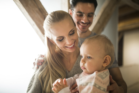 Glückliche junge Eltern, die zu Hause Zeit mit ihrem kleinen Mädchen verbringen, lizenzfreies Stockfoto