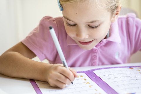 Smiling little girl writing alphabet stock photo