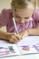 Lächelndes kleines Mädchen schreibt Zahlen in ein Schulheft - JFEF00893