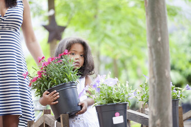 Mädchen trägt Pflanzgefäß im Freien - ISF17855