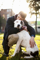 Man hugging dog in park - ISF17899