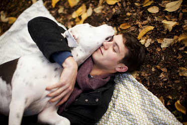 Mann und Hund umarmen sich auf einer Picknickdecke - ISF17904