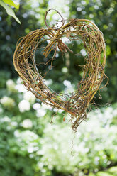 A heart shape made out of woven twigs, hanging from a tree. Simple decorations. - MINF02966