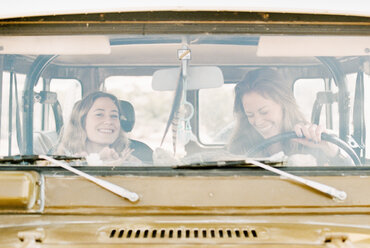 Zwei Frauen auf einem Roadtrip in der Wüste, in einem Geländewagen fahrend. - MINF02978