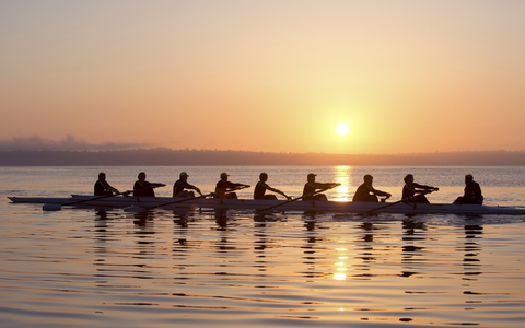 Neun Personen rudern bei Sonnenuntergang, lizenzfreies Stockfoto