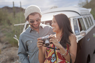 Young woman holding camera with boyfriend on road trip, smiling - ISF18026