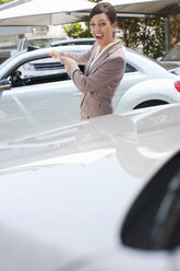 Excited woman pointing to new car - ISF18069