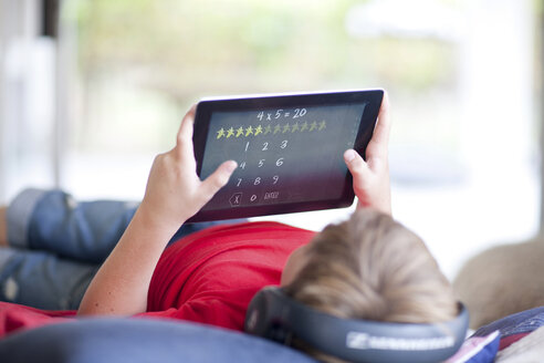 Junge auf dem Bett, der Musik hört und ein digitales Tablet benutzt - ISF18073