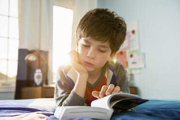 Junge liegt auf dem Bett und liest ein Buch - ISF18146