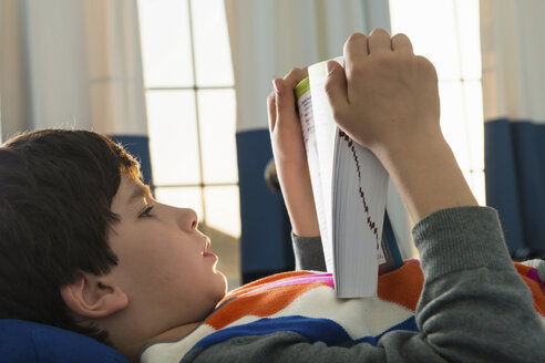 Junge liegt auf dem Bett und liest ein Buch - ISF18147