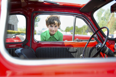 Junge schaut durch das Fenster eines Oldtimers - ISF18237