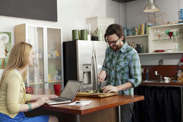 Woman on laptop computer, man chopping vegetables - ISF18264