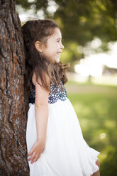 Porträt eines Mädchens, das sich lächelnd an einen Baumstamm lehnt - ISF18270