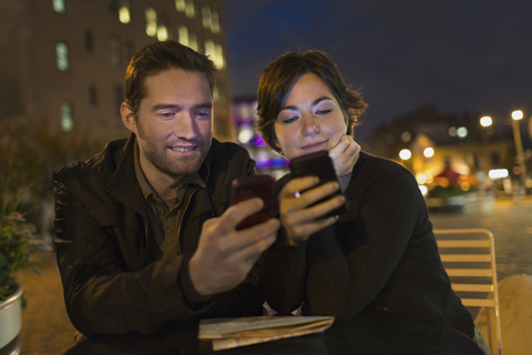 Pärchen benutzt Mobiltelefone im Freien, lizenzfreies Stockfoto