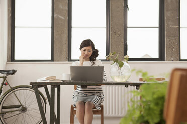 Junge Frau sitzt am Tisch mit Computer - ISF18318