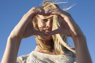 Portrait of young woman making heart sign, Breezy Point, Queens, New York, USA - ISF18331