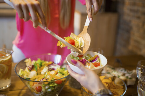 Nahaufnahme einer Frau, die einen Salat für einen Freund beim Abendessen zu Hause anrichtet - AWF00170