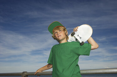 Porträt eines Jungen, der ein Skateboard über der Schulter hält - ISF18466