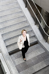 Smiling businesswoman walking downstairs - GIOF04004