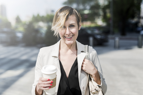 Porträt einer lächelnden Geschäftsfrau mit Coffee to go, lizenzfreies Stockfoto