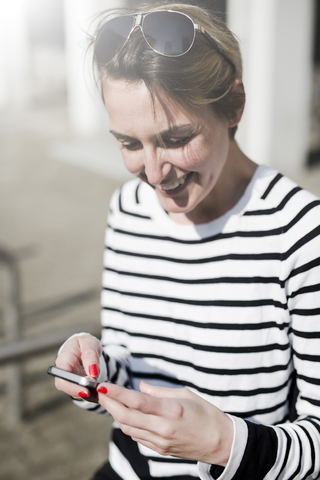 Lächelnde Frau schaut auf ihr Handy, lizenzfreies Stockfoto