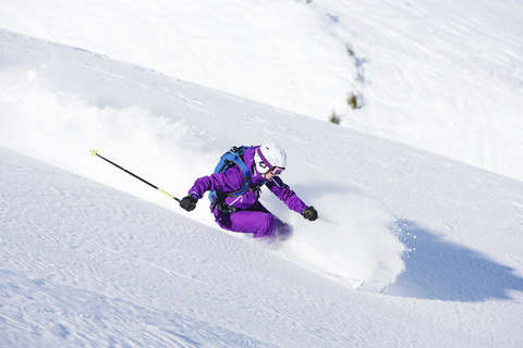 Weibliche Skifahrerin bei Geschwindigkeit bergab, lizenzfreies Stockfoto