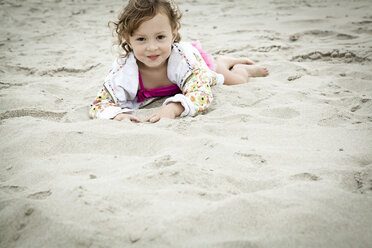 Porträt eines weiblichen Kleinkindes, das im Sand liegt - ISF18590