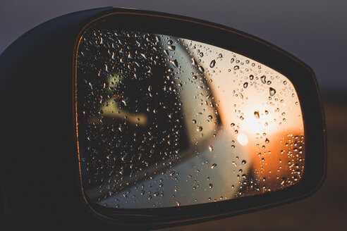 Regentropfen, die sich bei Sonnenuntergang im Rückspiegel eines Autos spiegeln - ACPF00146