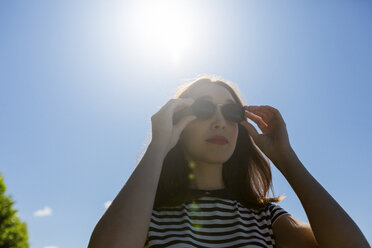 Portrait of young woman at backlight wearing sunglasses - GIOF04046