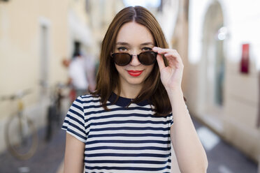 Italy, Bardolino, portrait of smiling young woman with sunglasses - GIOF04058