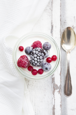 Ein Glas griechischer Joghurt mit gefrorenen Beeren, lizenzfreies Stockfoto