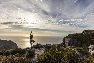 South Africa, Cape Town, Table Mountain, woman doing yoga on a rock at sunset - DAWF00683