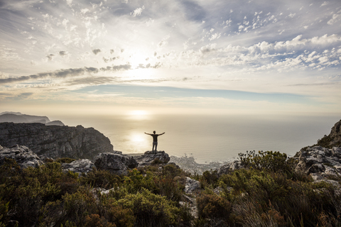 Südafrika, Kapstadt, Tafelberg, Mann steht auf einem Felsen bei Sonnenuntergang, lizenzfreies Stockfoto
