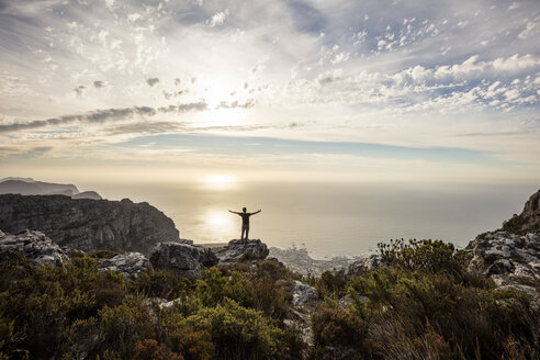 South Africa, Cape Town, Table Mountain, man standing on a rock at sunset - DAWF00684