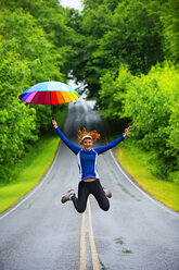 Jugendliches Mädchen springt mit Regenschirm auf die Straße, Bainbridge Island, Washington, USA - ISF18614