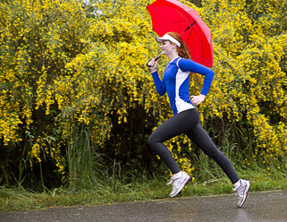 Jugendliches Mädchen joggt mit Regenschirm auf der Straße, Bainbridge Island, Washington, USA - ISF18615