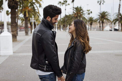 Spanien, Barcelona, lächelndes junges Paar auf Promenade mit Palmen - MAUF01560