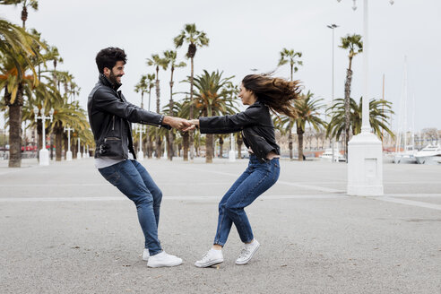 Spanien, Barcelona, glückliches junges Paar, das sich auf einer Promenade mit Palmen amüsiert - MAUF01561