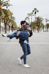 Spanien, Barcelona, glücklicher junger Mann mit Freundin auf Promenade mit Palmen - MAUF01563