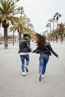 Spanien, Barcelona, glückliches junges Paar läuft auf Promenade mit Palmen - MAUF01564