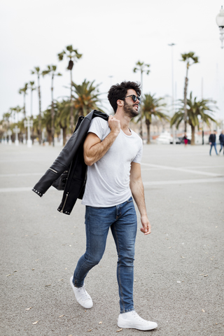 Spanien, Barcelona, junger Mann geht auf Promenade mit Palmen, lizenzfreies Stockfoto