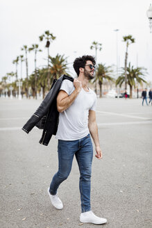 Spanien, Barcelona, junger Mann geht auf Promenade mit Palmen - MAUF01576