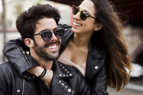 Porträt eines glücklichen jungen Paares mit Sonnenbrillen und Lederjacken - MAUF01586