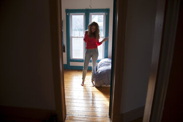 Teenager standing in bedroom listening to MP3 player - ISF18640