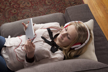 Mädchen auf dem Sofa liegend mit digitalem Tablet - ISF18644