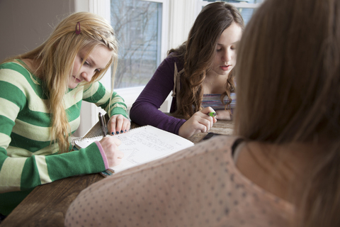 Mädchen sitzen am Tisch und lernen, lizenzfreies Stockfoto