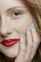 Cropped shot of young woman with curly red hair wearing make up, hand on chin - ISF18662